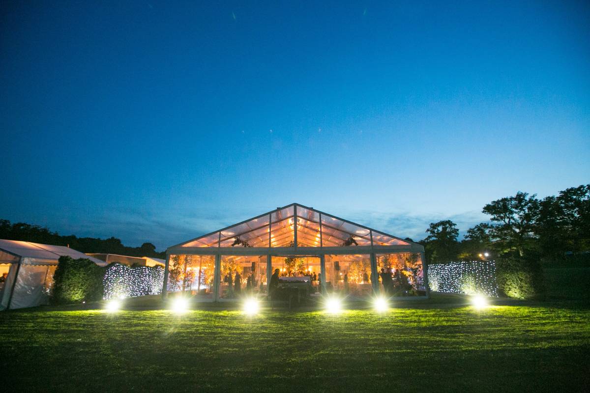 LIghting inside and outside a completely clear marquee creates a dramatic spectacle. At dusk