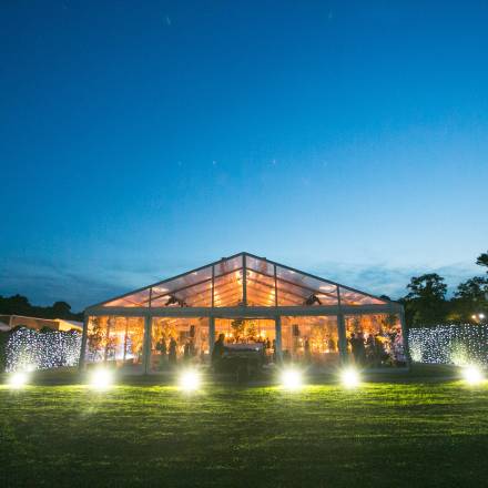 LIghting inside and outside a completely clear marquee creates a dramatic spectacle. At dusk