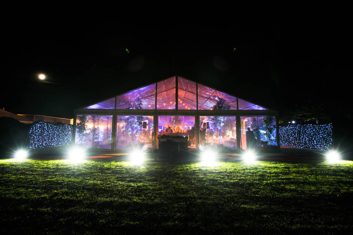 Night time lighting inside and outside a completely clear marquee creates a dramatic spectacle