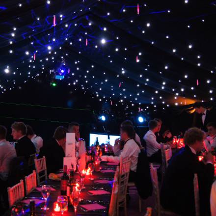 Party dining in a blacked out marquee with twinkly starlight ceiling