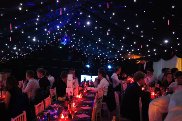 Party dining in a blacked out marquee with twinkly starlight ceiling