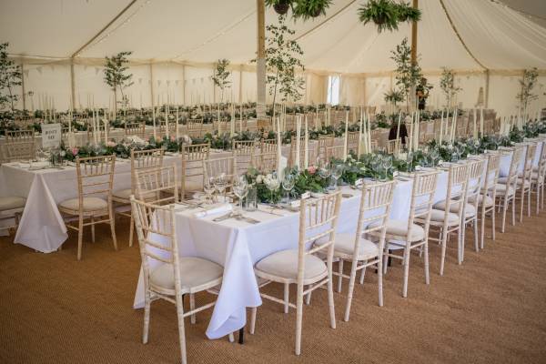 Romantically styled wedding reception inside a traditional marquee with wooden poles
