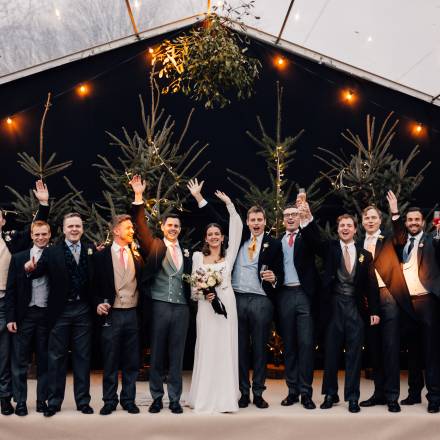Bride and all the boys in front of Christmas trees