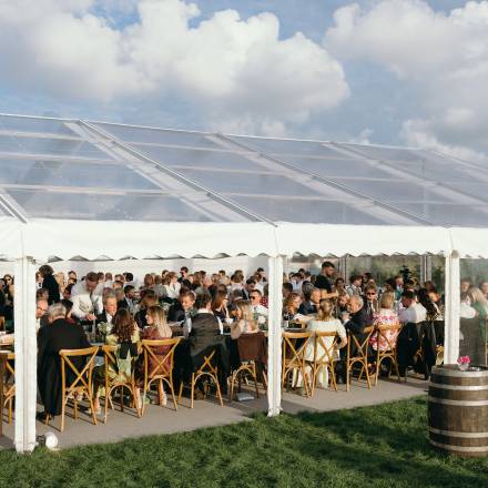 Seated guests in a open sided transparent wedding marquee