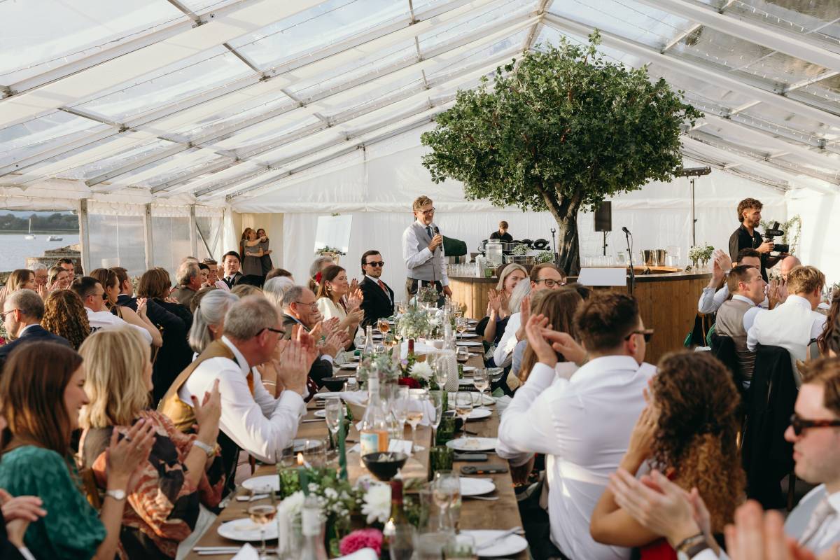 Applauding a speech inside a clear wedding marquee