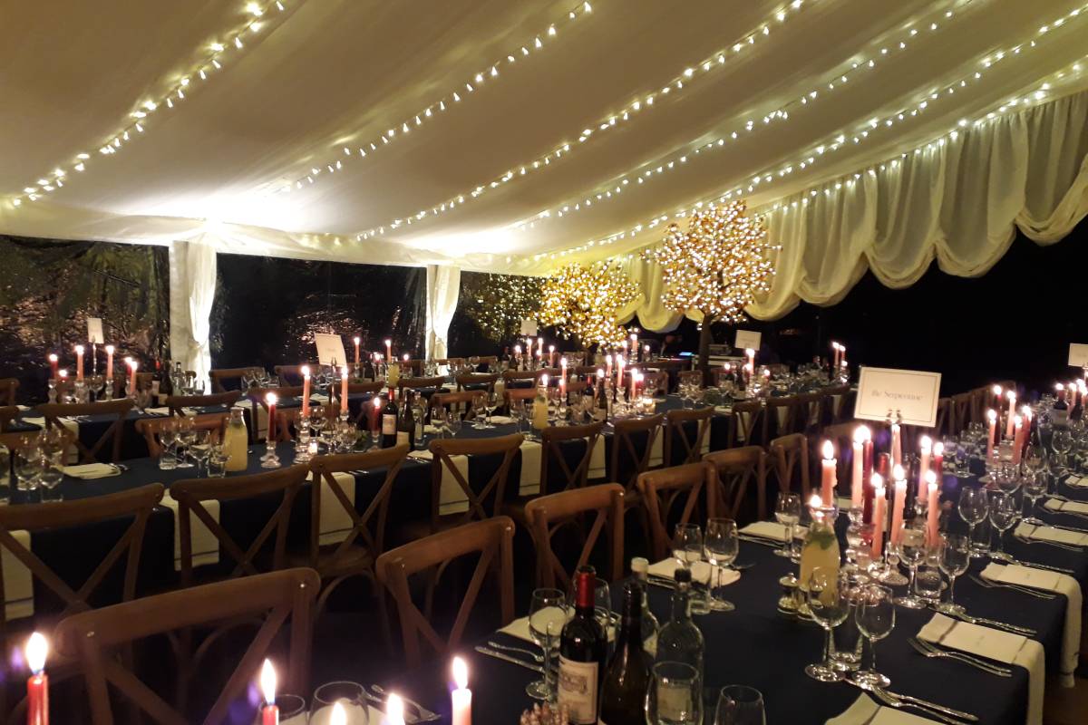 A winter marquee - dark tablecloths, candles, fairy lights - for a cosy Christmas party