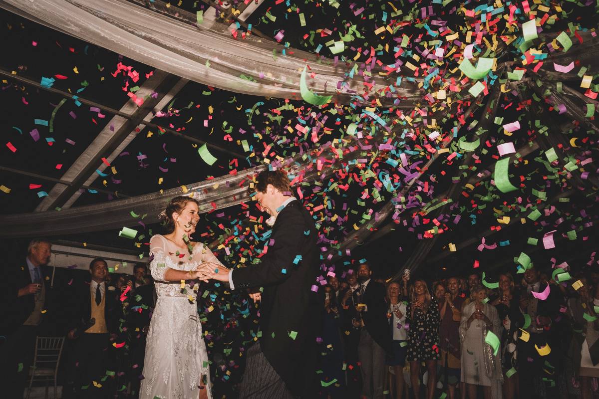 Bride and groom dance under a shower of confetti in a clear marquee