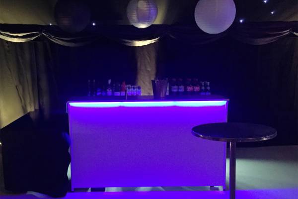 White bar lit purple in blacked out marquee