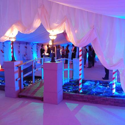 Entrance to Venice themed marquee with a bridge over a bubble wrap river with a gondola