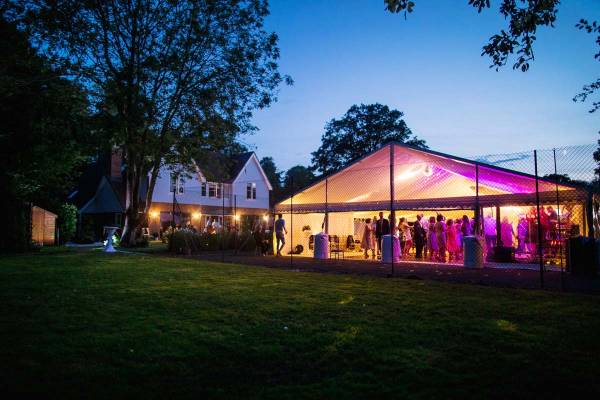 Frame tent with a clear front on a tennis court in a large garden