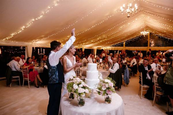 Classic wedding reception with fairy light canopy, clear walls and big candlesticks