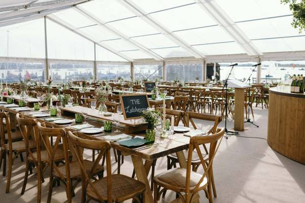 Fashionable clear roof marquee with rustic tables and cross back chairs
