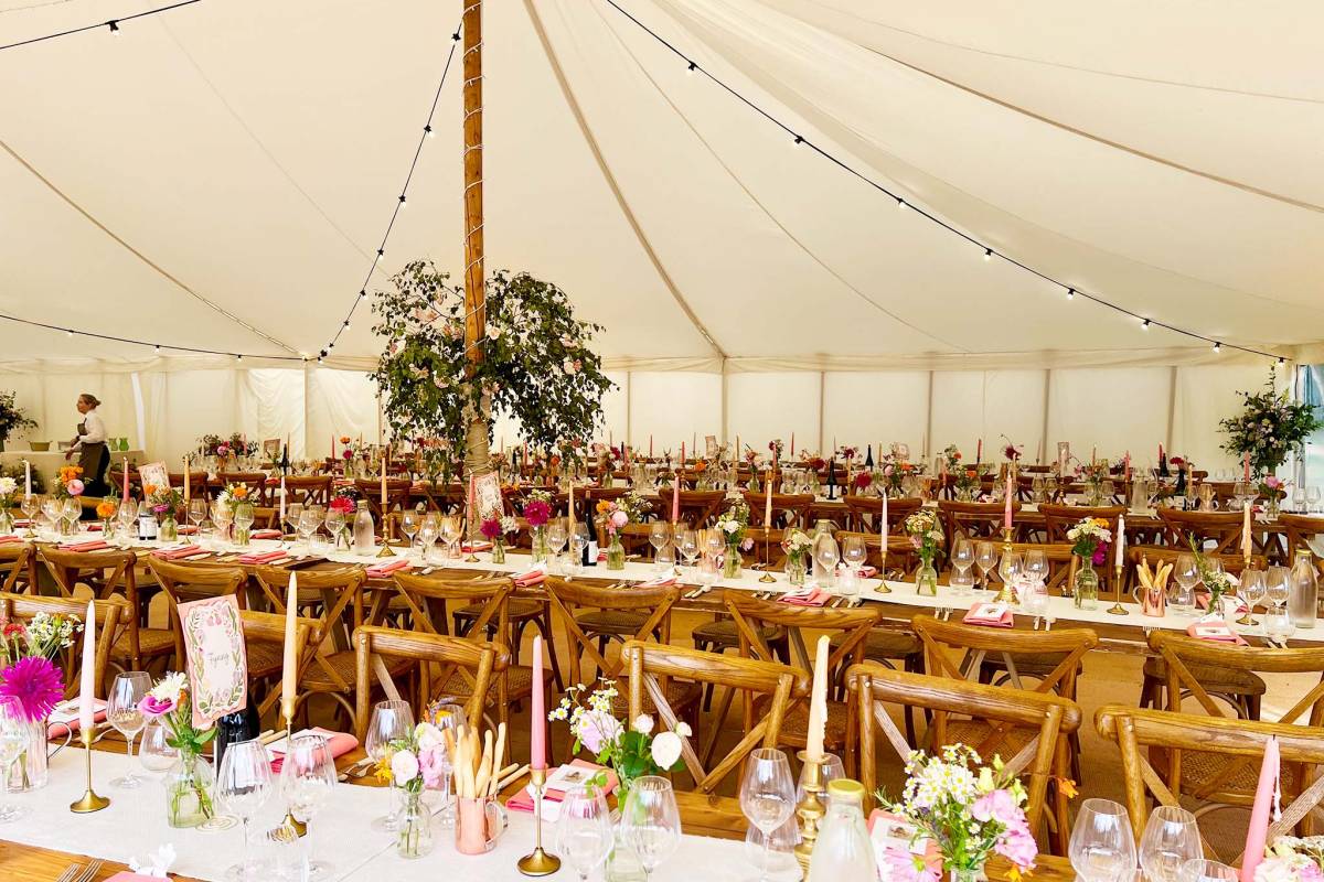 Lined up trestle tables with little flower vases, candles and table runners