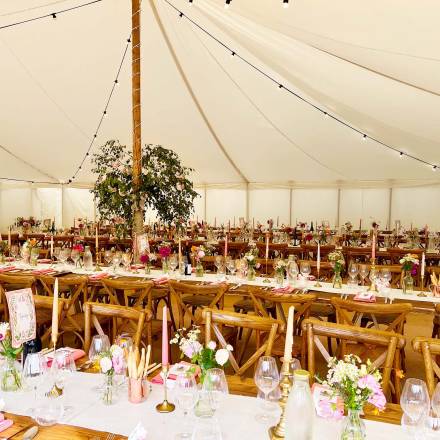 Lined up trestle tables with little flower vases, candles and table runners