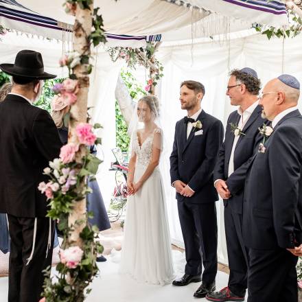 Under a prettily decorated Jewish wedding canopy