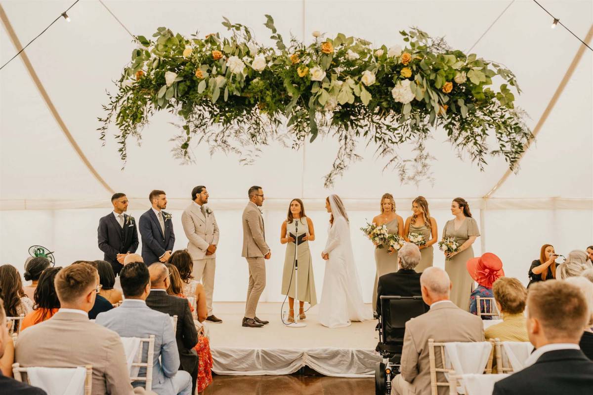 Wedding blessing under hanging flowers in a marquee