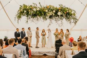 Wedding blessing under hanging flowers in a marquee