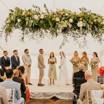 Wedding blessing under hanging flowers in a marquee
